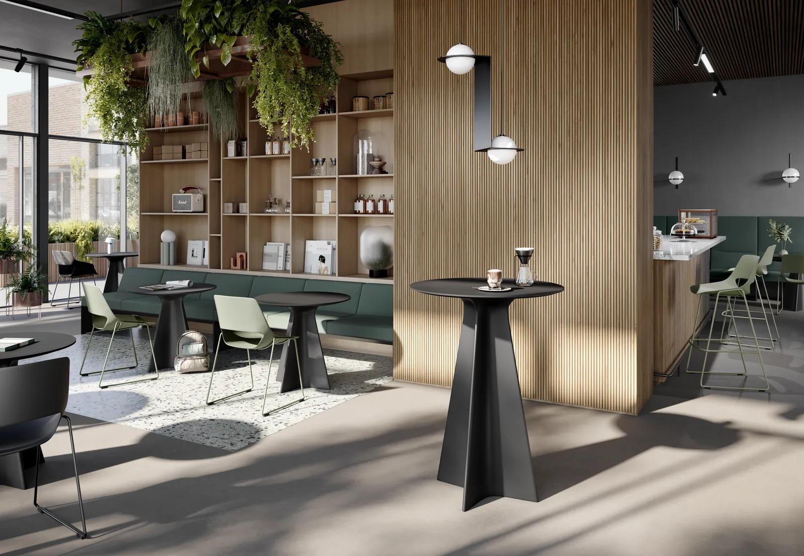 Cafeteria mit hoher Regalwand, Stehtisch im Vordergrund und Sitzgruppen an der Fensterseite