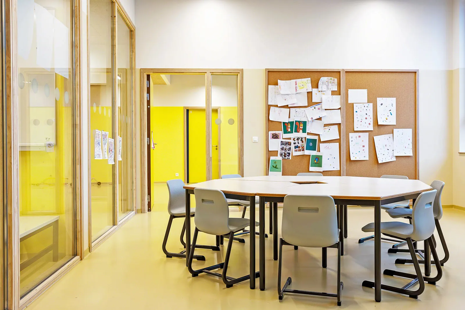 Offener Lernbereich einer Schule mit niedrigen Regalen als Raumteiler, Sitzhockern und Fensterfront